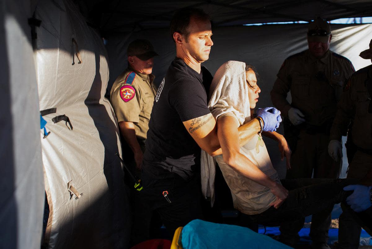 Firefighter EMT William Dorsey lifts a migrant woman suffering from heat exhaustion onto a stretcher in the border community of Eagle Pass, Texas on June 26, 2023.