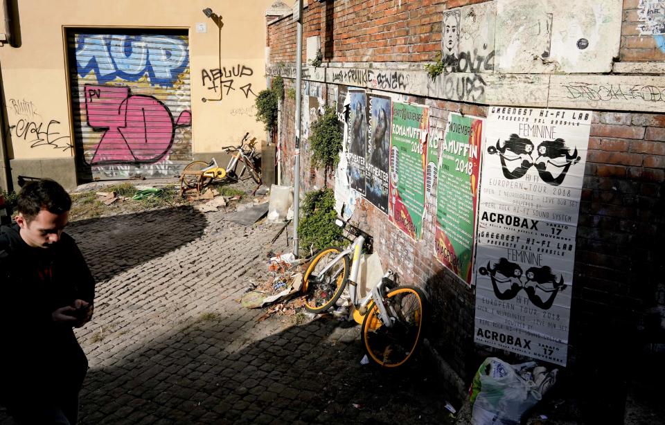 Dismantled bicycles belonging to a bike-sharing company lie abandoned in a graffiti and poster covered alleyway in Rome's Trastevere historical neighborhood, Monday, Nov. 12, 2018. Rome’s monumental problems of garbage and decay exist side-by-side with Eternal City’s glories. (AP Photo/Andrew Medichini)