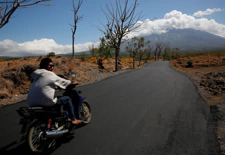 A man rides his motorcycle in the direction of Mount Agung, a volcano on the highest alert level, near Kubu, on the resort island of Bali, Indonesia September 25, 2017. REUTERS/Darren Whiteside