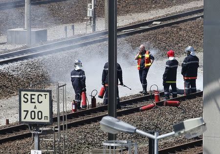 Firemen inspect the tracks after workers operating on the MyFerryLink car and passenger ferry boats set tires into fire at the entrance of the Eurotunnel Channel Tunnel linking Britain and France in Coquelles near Calais, northern France, June 30, 2015. REUTERS/Vincent Kessler