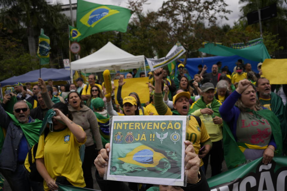 A supporter of Brazilian President Jair Bolsonaro holds a sign that reads in Portuguese: "Intervention now!" outside a military base during a protest against his reelection defeat in Sao Paulo, Brazil, Thursday, Nov. 3, 2022. Some supporters are calling on the military to keep Bolsonaro in power, even as his administration signaled a willingness to hand over the reins to his rival, President-elect Luiz Inacio Lula da Silva. (AP Photo/Matias Delacroix)