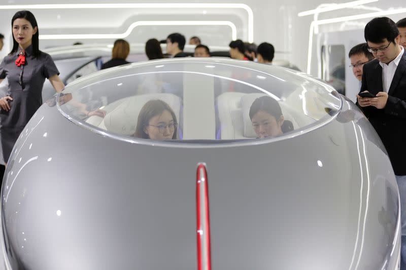 Visitors sit in a concept model at the booth of FAW Group car brand Hongqi at the Auto China 2018 motor show in Beijing