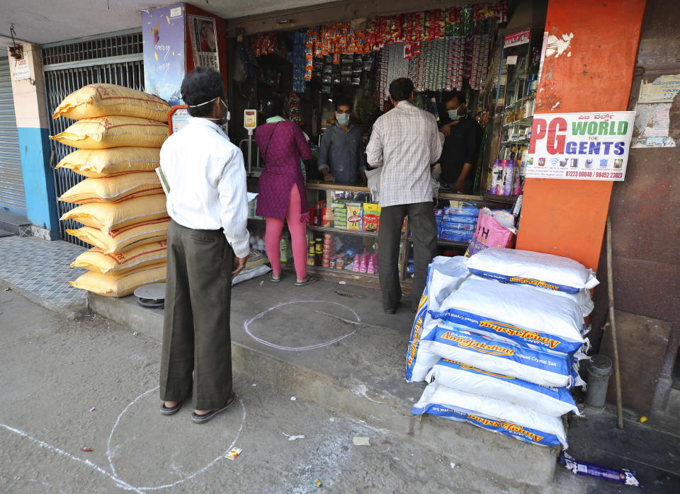 Indians stand in marked positions to maintain physical distance outside a grocery store during lockdown in Bangalore, India, Thursday, March 26, 2020. The unprecedented lockdown keeping India's 1.3 billion people at home for all but essential trips to places like supermarkets or pharmacies is meant to keep virus cases from surging above the 553 already recorded and overwhelming an already strained health care system. The new coronavirus causes mild or moderate symptoms for most people, but for some, especially older adults and people with existing health problems, it can cause more severe illness or death. (AP Photo/Aijaz Rahi)