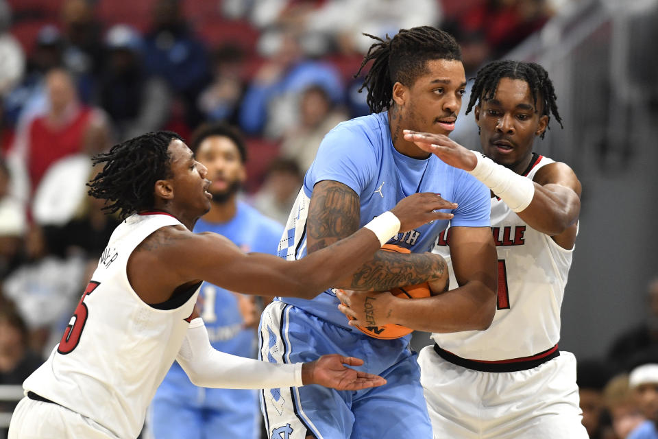 North Carolina forward Armando Bacot (5) tries to keep the ball away from Louisville guard Hercy Miller (15), left, and forward Jae'Lyn Withers (24) during the second half of an NCAA college basketball game in Louisville, Ky., Saturday, Jan. 14, 2023. North Carolina won 80-59. (AP Photo/Timothy D. Easley)