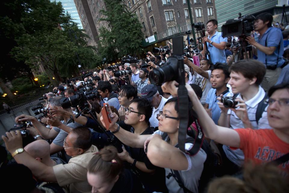 People crowd a bridge that goes over 42nd St as they take photos of Manhattanhenge in New York