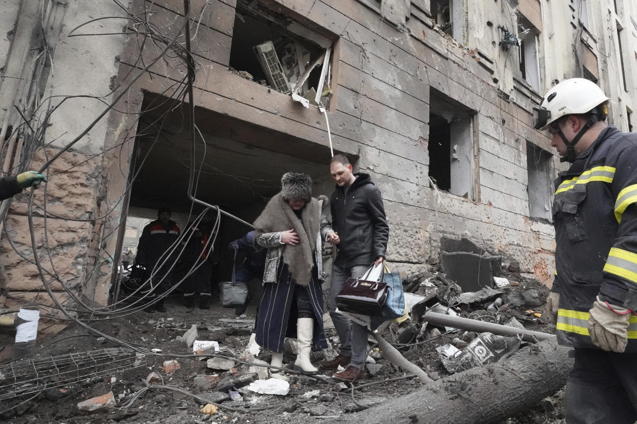 A man helps a lady to walk out from a residential building which was hit by a Russian rocket, in the city center of Kharkiv, Ukraine, Sunday, Feb. 5, 2023. (AP Photo/Andrii Marienko)