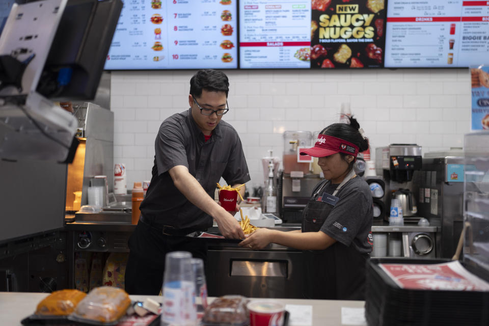 Lawrence Cheng, left, whose family owns seven Wendy's locations south of Los Angeles, works with part-time employee Adriana Ruiz at his Wendy's restaurant in Fountain Valley, Calif., June 20, 2024. When California’s minimum wage increase went into effect in April, fast food workers across the state went from making $16 to $20 overnight. It's already having an impact, according to local operators for major fast food chains, who say they are reducing worker hours and raising menu prices as the sudden increase in labor costs leaves them scrambling for solutions. (AP Photo/Jae C. Hong)