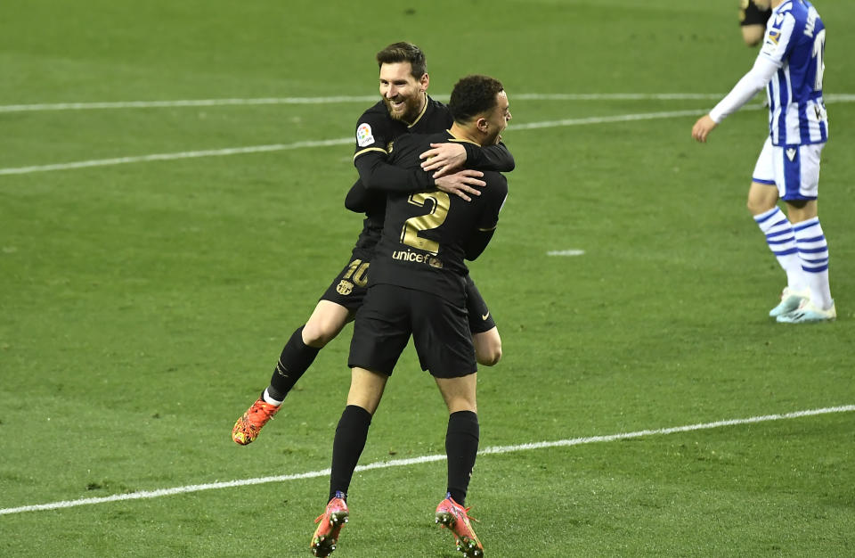 Sergiño Dest celebra con Lionel Messi tras anotar el tercer gol del Barcelona en la visita a la Real Sociedad por la Liga española, el domingo 21 de marzo de 2021. (AP Foto/Alvaro Barrientos)