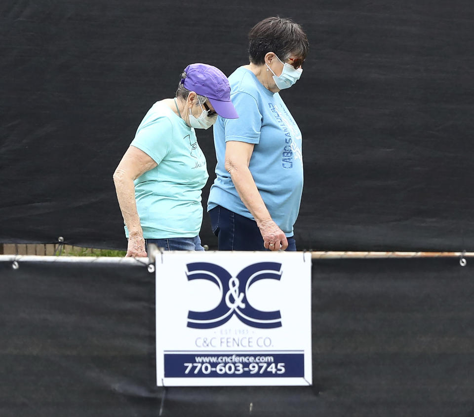 A pair of women behind a blackened fence where quarantined Grand Princess cruise ship passengers are isolated in a housing area at Dobbins Air Reserve Base on Thursday, March 12, 2020, in Marietta, Ga. "Prior to arriving here, the passengers were medically screened by the U.S. Department of Health and Human Services and Centers for Disease Control and Prevention," said Col. Craig McPike, Dobbins installation commander. "The passengers who were asymptomatic were transferred here and other federal military installations for COVID-19 testing and quarantine." Should any individuals be identified as ill during their quarantine period, the Department of Health & Human Services, the lead federal agency, has procedures in place to transport them to a local civilian hospital. "CDC is fully responsible for all aspects of the quarantine operation, and Dobbins personnel will have no contact with these passengers. (Curtis Compton/Atlanta Journal-Constitution via AP)