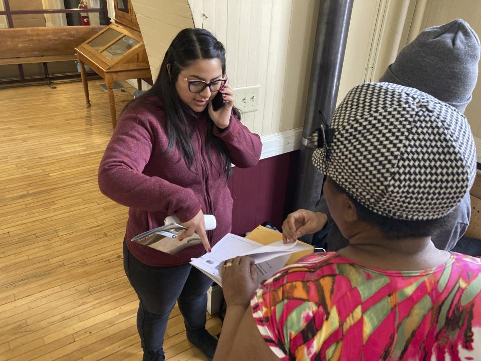 Karla Elizalde helps a Haitian immigrant couple in St. Johnsbury, Vt., on Thuesday March 23, 2023. The couple and their three children, aged 17, 15, and 9, were dropped off in arrived in St. Johnsbury on Thursday by the U.S. Border Patrol. The family asked that their photos only be taken from behind. The U.S. Border Patrol says agents are releasing some immigrants who were apprehended in Vermont after they entered the country illegally and dropping them off where they can catch public transportation. (AP Photo/Wilson Ring)