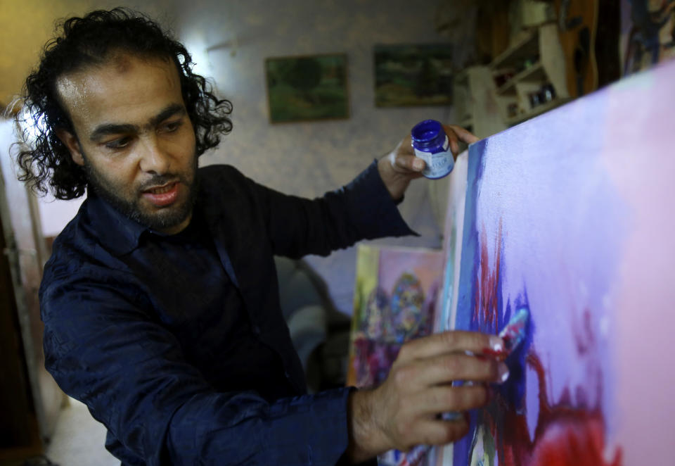 In this photo taken Wednesday, May 14, 2014, Palestinian artist Ismail Dahlan, 36, paints at his studio in Beit Lahiya, in the northern Gaza Strip, Wednesday, May 14, 2014. Dahlan is among 45 Gaza artists showing their work in a West Bank exhibit, a rare showcase for painters living in the Hamas-ruled territory that is largely sealed off by an Israeli-Egyptian border blockade. (AP Photo/Adel Hana)