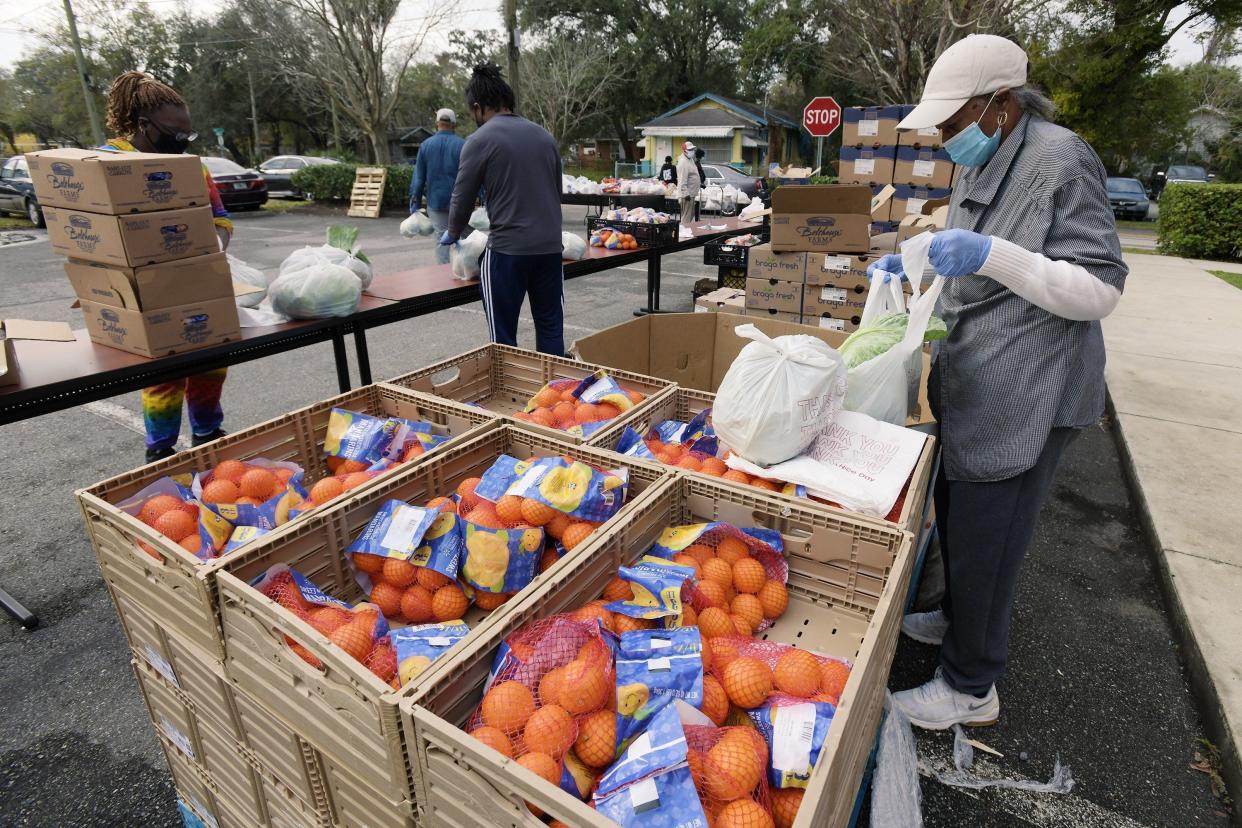 Volunteer Gloria Williams bags up heads of fresh cabbage to hand out to neighborhood residents at a Grunthal Street food distribution area in 2021.