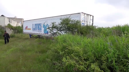 A police officer walks past an abandoned trailer full of bodies in Tlajomulco de Zuniga, Jalisco, Mexico September 15, 2018 in this still image taken from a video obtained September 17, 2018. REUTERS TV/via REUTERS