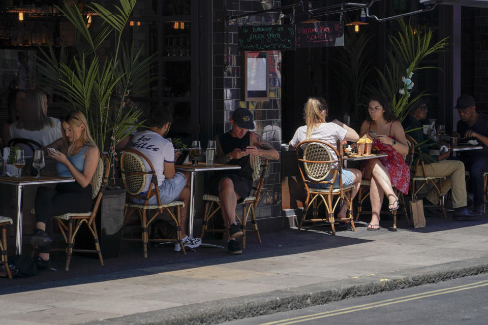 People sit at outdoor tables at a restaurant in Soho, in London, Monday, June 14, 2021. British Prime Minister Boris Johnson is expected to confirm Monday that the next planned relaxation of coronavirus restrictions in England will be delayed as a result of the spread of the delta variant first identified in India. (AP Photo/Alberto Pezzali)