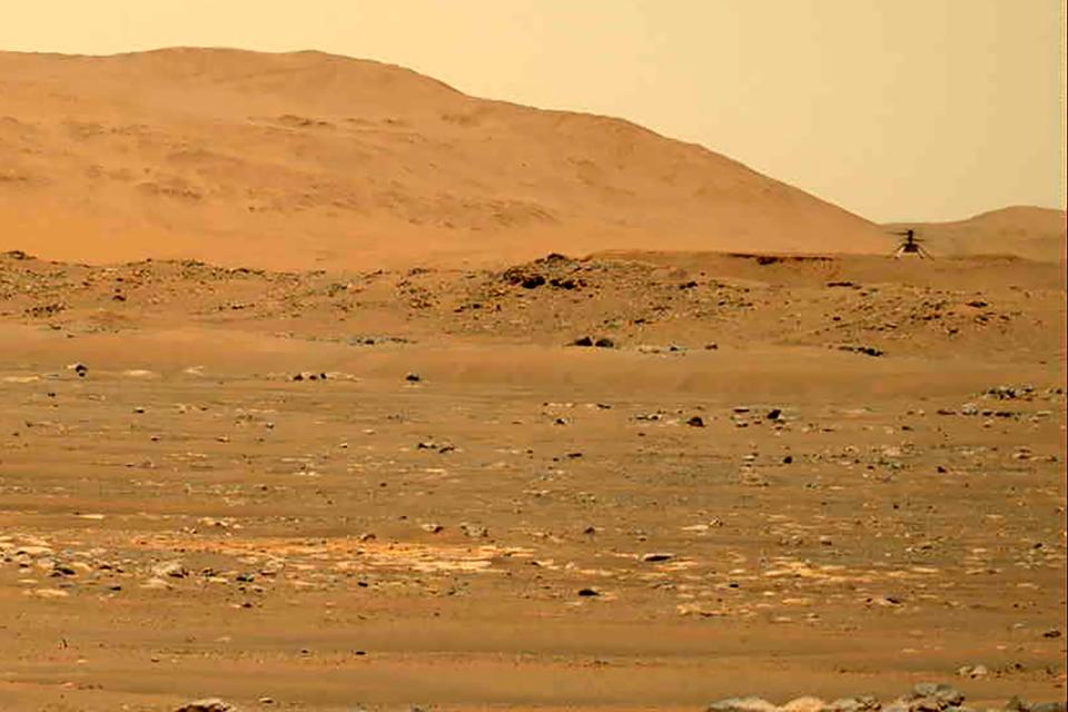 In this April 30, 2021, file image taken by the Mars Perseverance rover and made available by NASA, the Mars Ingenuity helicopter, right, flies over the surface of the planet.