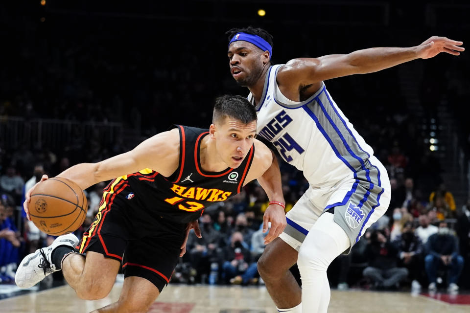 Atlanta Hawks guard Bogdan Bogdanovic (13) drives against Sacramento Kings guard Buddy Hield (24) in the first half of an NBA basketball game Wednesday, Jan. 26, 2022, in Atlanta. (AP Photo/John Bazemore)