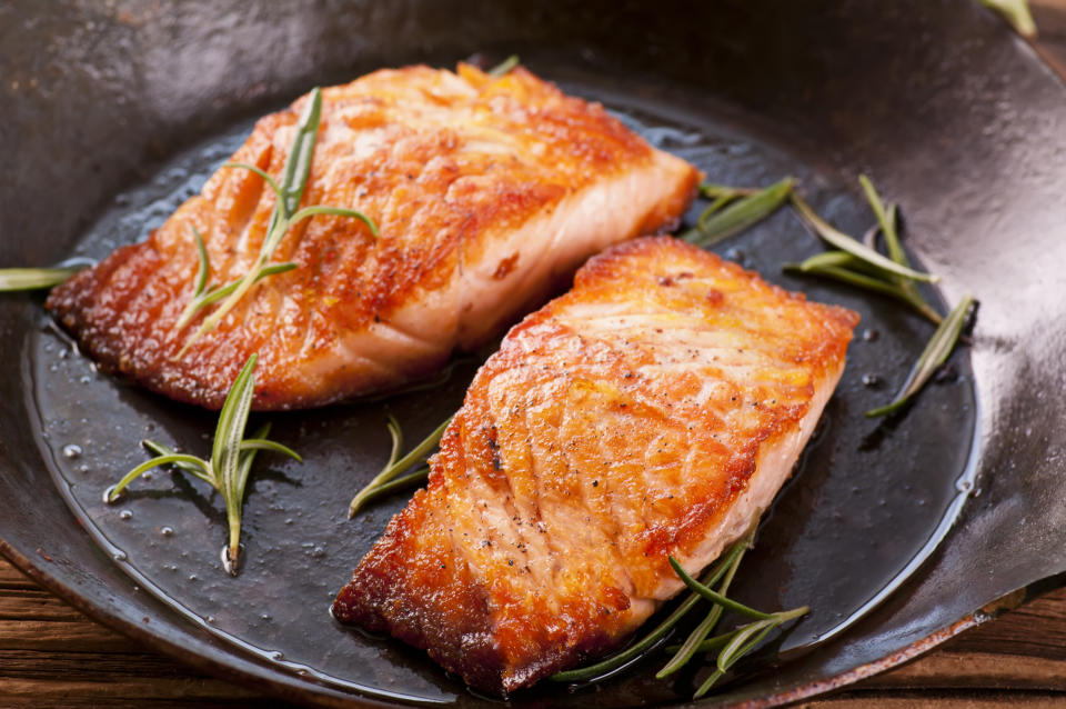 salmon steak as closeup in black iron fryer