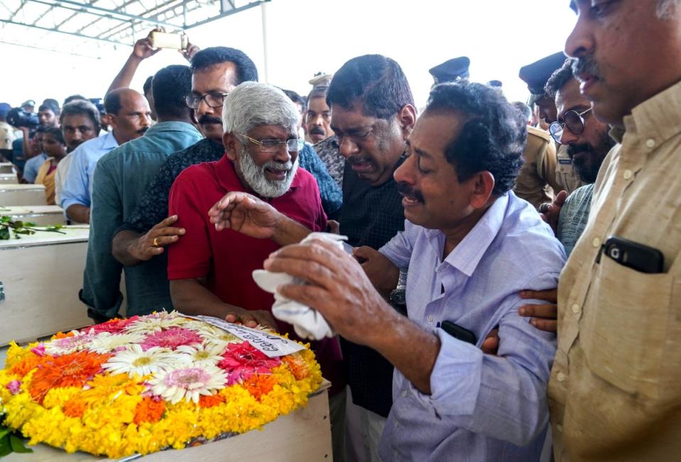 Relatives mourn near the deceased after the coffins' arrival on an Indian Air Force plane from Kuwait (AFP via Getty Images)