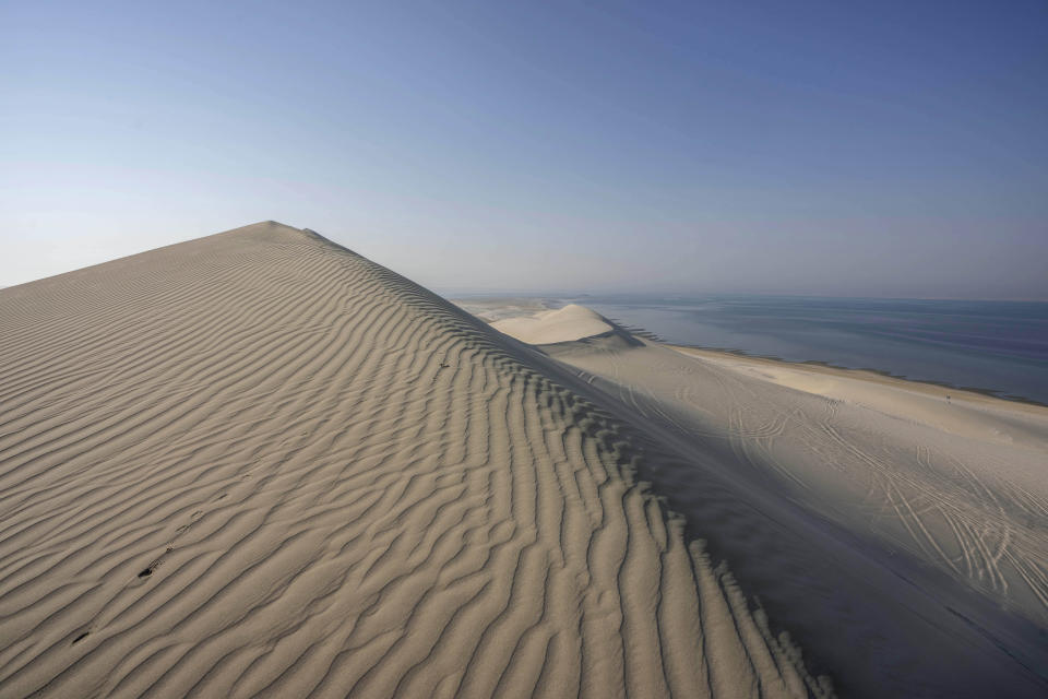 Sand dunes meet the Khor Al Adaid Inland Sea, on the border between Qatar and Saudi Arabia, in Mesaieed, Al Wakrah state, Qatar, Thursday, Oct. 20, 2022. (AP Photo/Nariman El-Mofty)