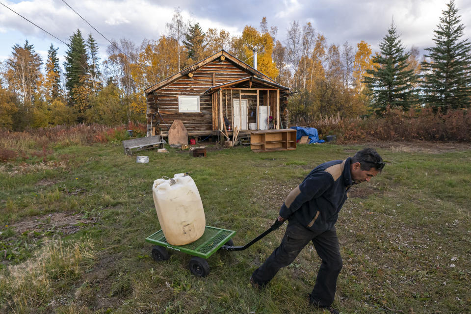 Ben Stevens hauls fuel to his river boat before leaving for the Stevens' family hunting camp on the Yukon River on Tuesday, Sept. 14, 2021, in Stevens Village, Alaska. Two salmon species have all but disappeared from Alaska's Yukon River this year, prompting the state to shut down fishing in an effort to save them. (AP Photo/Nathan Howard)