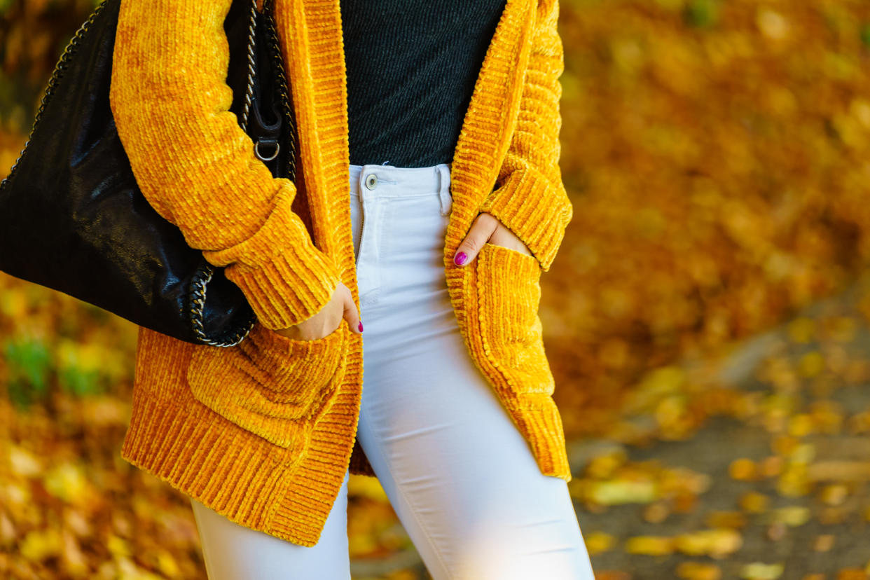 Unrecognizable woman wearing long orange warm cardigan sweater. Autumnal fashion, autumn season styled outfits. Female having a walk in park