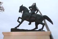 A tarp still covers part of a statue during the unveiling ceremony for a statue titled Rumor's of War by artist Kehinde Wiley at the Virginia Museum of Dine Arts in Richmond, Va., Tuesday, Dec. 10, 2019. The monumental bronze sculpture of a young black man astride a galloping horse was unveiled Tuesday, set to be permanently installed in Virginia's capital city, not far from the Confederate monument it mimics. (AP Photo/Steve Helber)