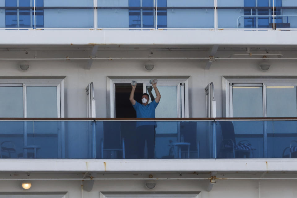 A passenger exercises using two water bottles on the quarantined Diamond Princess cruise ship Wednesday, Feb. 19, 2020, in Yokohama, near Tokyo. Passengers tested negative for COVID-19 will start disembarking Wednesday. (AP Photo/Jae C. Hong)