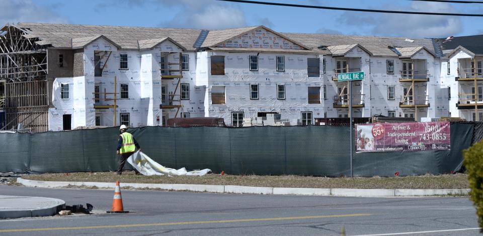 A worker corrals a long piece of construction debris along the perimeter of the 55 plus apartment complex just off Perry Ave in Buzzards Bay on April 8, 2021. Work on the project has stalled because of the pandemic.
