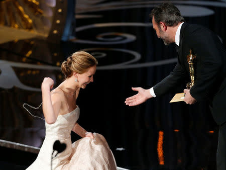 FILE PHOTO: Actress Jennifer Lawrence is helped by presenter French actor Jean Dujardin after she tripped walking up the stairs to accept the award for best actress for her role in "Silver Linings Playbook" at the 85th Academy Awards in Hollywood, California February 24, 2013. REUTERS/Mario Anzuoni/File Photo