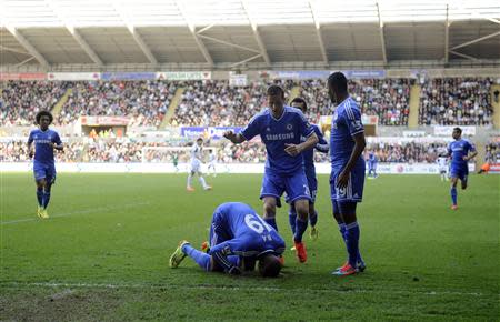 Chelsea's Demba Ba (bottom) celebrates scoring a goal by kissing the turf during their English Premier League soccer match against Swansea City at the Liberty Stadium in Swansea, Wales, April 13, 2014. REUTERS/Rebecca Naden