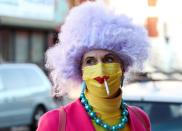 FILE PHOTO: A woman dressed up for Halloween as a Simpsons character smokes a cigarette through a protective mask in Brooklyn