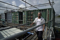 Arthur Lee, owner of MoVertical Farm, walks beside his shipping containers in Yuen Long, Hong Kong's New Territories Tuesday, Sept. 22, 2020. Operating on a rented 1,000 square meter patch of wasteland in the Hong Kong's rural area, Lee's MoVertical Farm utilizes around 30 of the decommissioned containers, to raise red water cress and other local vegetables hydroponically, which eliminates the need for soil. A few are also used as ponds for freshwater fish. (AP Photo/Kin Cheung)