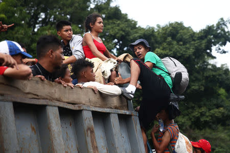 A Honduran migrant, part of a caravan trying to reach the U.S., climbs on a truck during a new leg of his travel in Zacapa, Guatemala October 17, 2018. REUTERS/Edgard Garrido