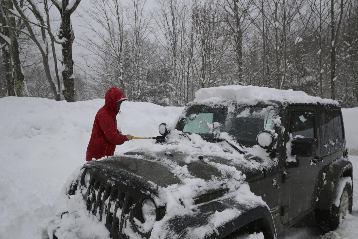 Michael Kloeti, cleans off his car after a winter hike in Stowe, Vt., on Tuesday March, 14, 2023. Kloeti and a friend hiked about five hours to visit a cabin on a hiking trail on the side of Mount Mansfield, Vermont's tallest peak. Kloeti said "it was awesome." The two hiked on the day a winter storm with heavy, wet snow hit the region that snarled highways, led to hundreds of school closings, canceled flights and caused thousands of power outages in parts of the Northeast on Tuesday. (AP Photo/Wilson Ring)
