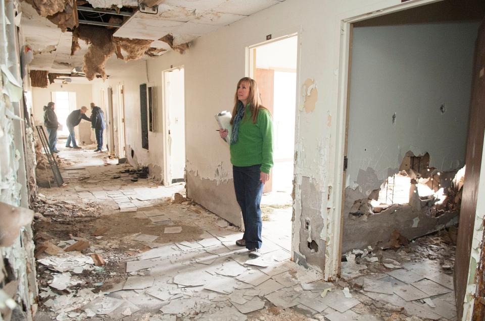 Jessica Lindbom, an environmental technologist with Quantum Environmental & Engineering Services, inspects a vandalized hallway in the old Waterside Building at Lakeshore Park in 2014. Demolition of 21 of the 23 buildings included removal of asbestos.