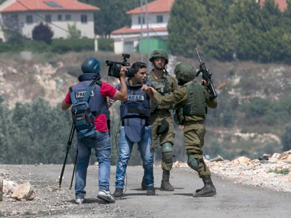 An Israeli soldier escorts a Palestinian journalist as Palestinian protesters clash with Israeli forces during a weekly demonstration against the expropriation of Palestinian land by Israel in the village of Kfar Qaddum, near Nablus in the occupied West Bank, on May 11, 2018: Getty