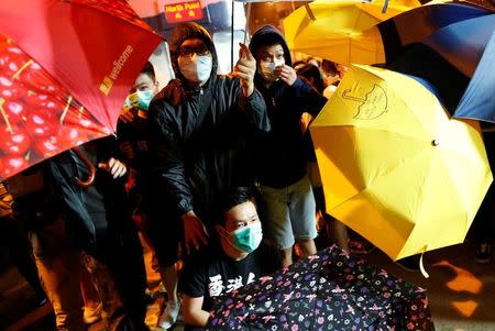 Demonstrators try to protect themselves from being pepper-sprayed during a protest against what they call Beijing's interference over local politics and the rule of law, a day before China's parliament is expected to announce their interpretation of the Basic Law in light of two pro-independence lawmakers' oath-taking controversy, in Hong Kong, China November 6, 2016. REUTERS/Tyrone Siu