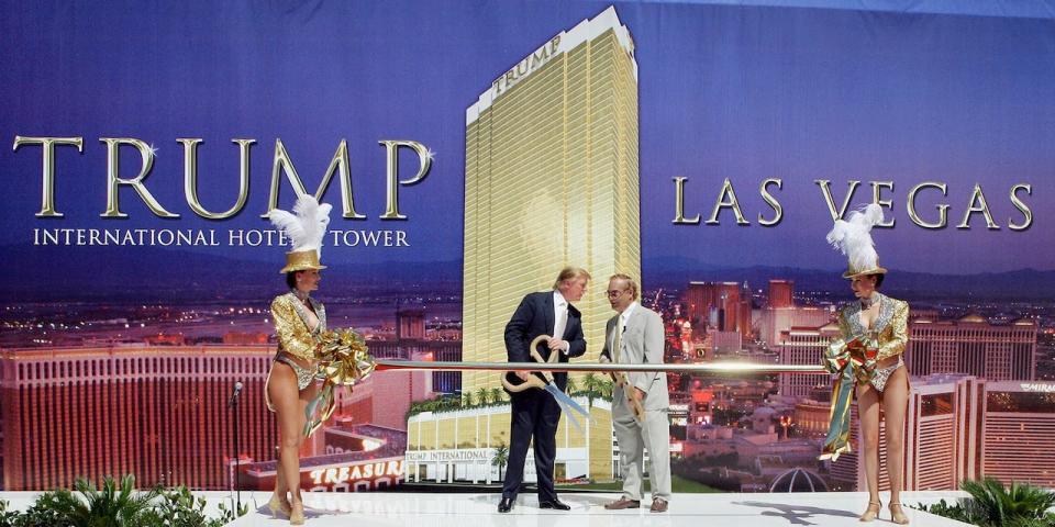 Showgirls flank Chairman and President of the Trump Organization Donald Trump (L) and Phil Ruffin, owner of the New Frontier Hotel and Casino, as they prepare to cut a ribbon at a ceremonial groundbreaking for the 64-story Trump International Hotel & Tower Las Vegas July 12, 2005 in Las Vegas, Nevada.