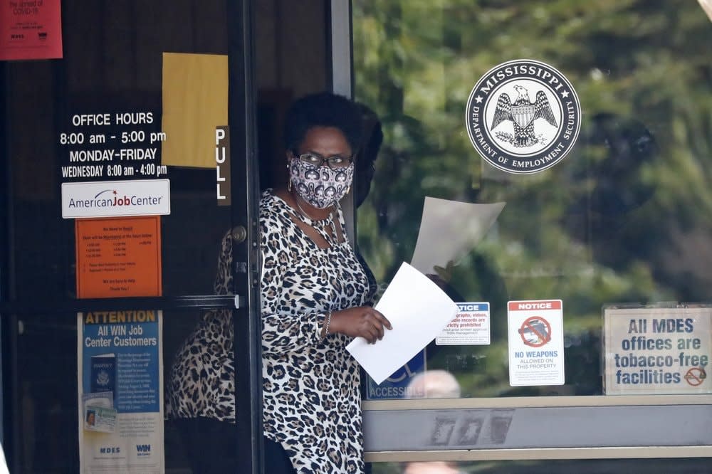 Worker wearing a mask to protect against coronavirus, holds an unemployment benefit application form as she waits for a client at the state WIN job center in Pearl, Miss. (AP Photo/Rogelio V. Solis, File)