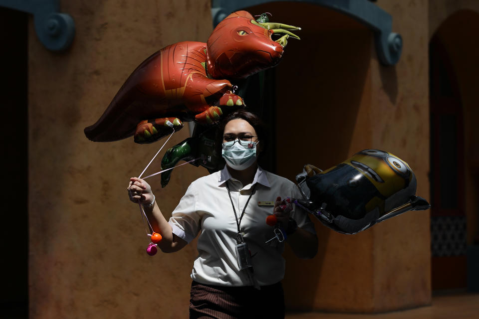 A staff wearing protective mask carries balloons for sale at Universal Studios at Resorts World Sentosa on 3 July, 2020 in Singapore. (PHOTO: Getty Images)