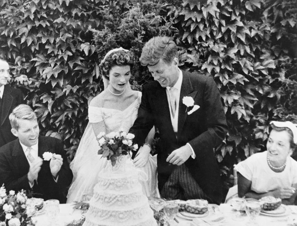The couple cut their wedding cake at the reception. Kennedy's brother Robert Kennedy (left) looks on. (Photo: Bettmann via Getty Images)