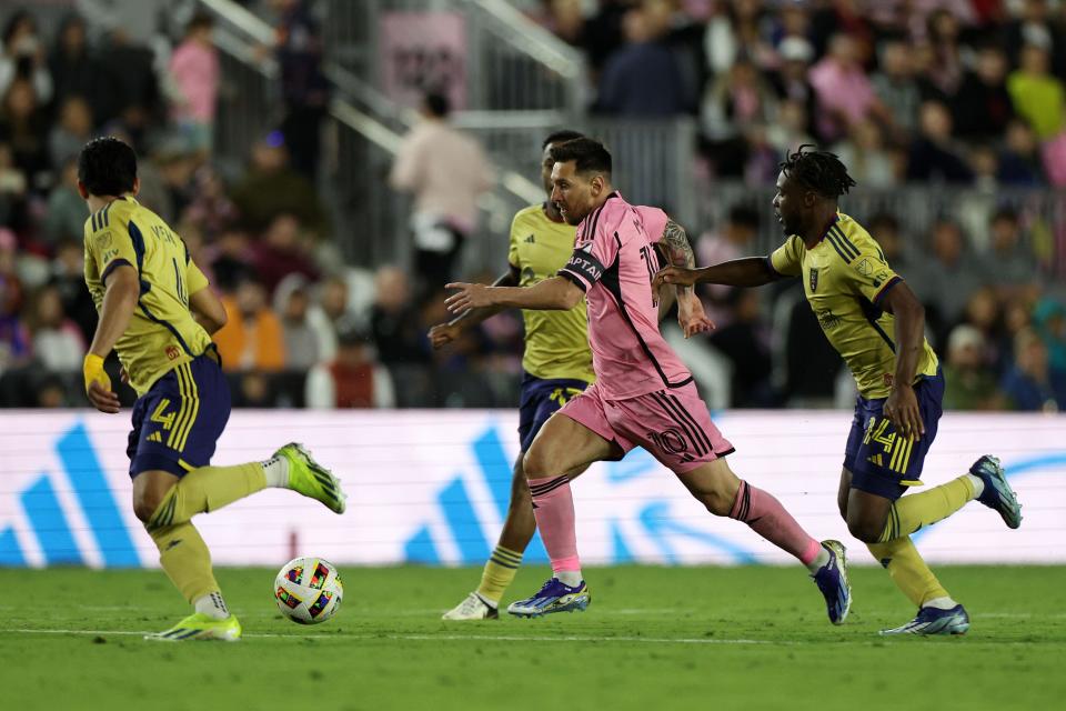 Lionel Messi dribbles the ball while surrounded by Real Salt Lake players.