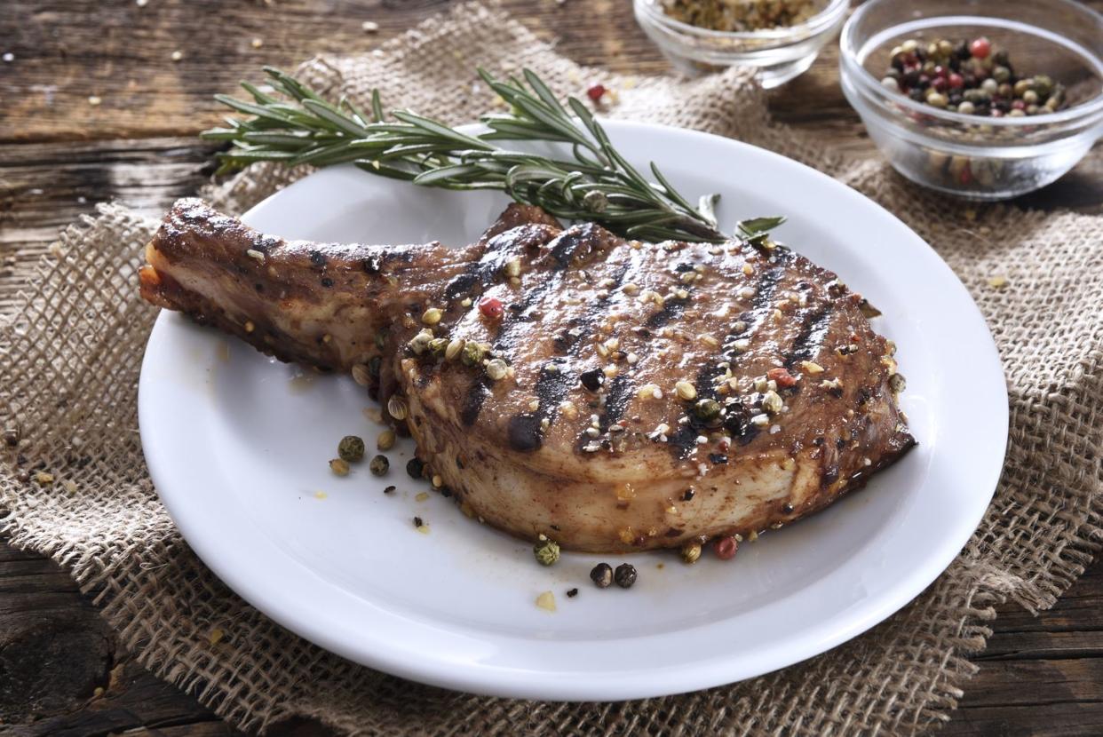 juicy grilled pork chop with spices on a white plate