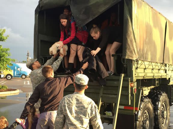 In this image released by the Louisiana National Guard (LANG), soldiers help two women and a dog out of the back of a high-water vehicle in Baton Rouge, La., after being rescued in Millerville, Sunday. The LANG has rescued more than 3,400 people and 400 pets during search and rescue operations since operations began 48 hours ago.