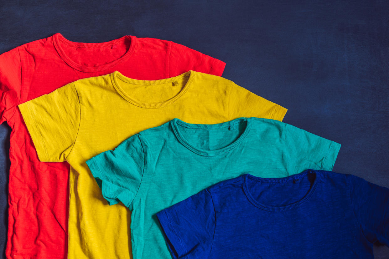 Colorful collection of t-shirts on wooden background.