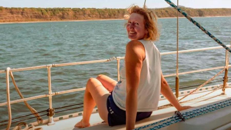 Sarah Packwood sitting on the deck of her yacht, Theros, looking over her shoulder and smiling.