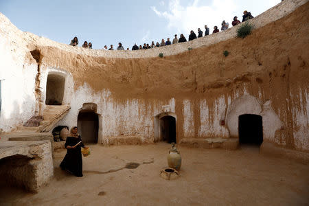 Tunisian tourists watch as Saliha Mohamedi, 36, walks around her troglodyte house on the outskirts of Matmata, Tunisia, February 4, 2018. "I don't want to leave my house, it would be as if I was throwing my life and my traditions away," Saliha said. REUTERS/Zohra Bensemra