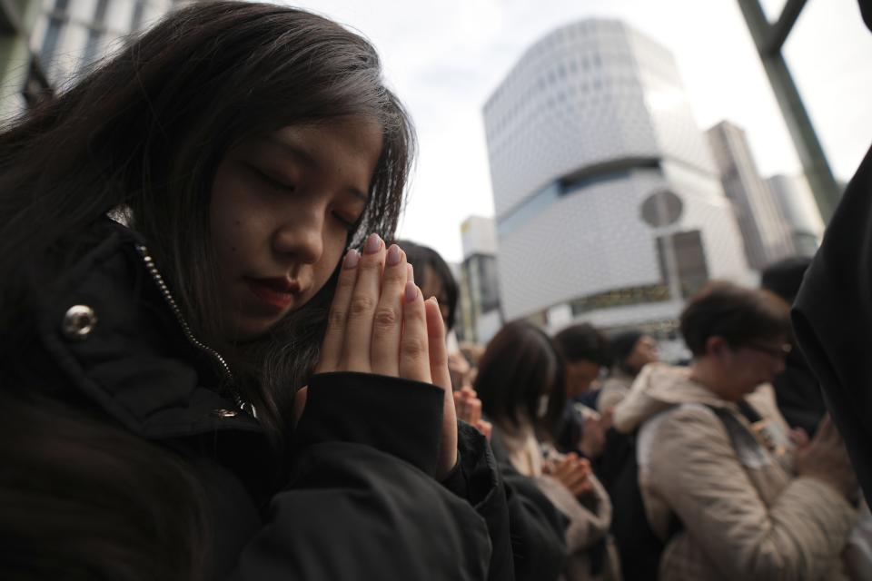 Bystanders pray when an annual tribute started at 2:46 p.m. for the victims of a 2011 disaster Monday, March 11, 2024, in Tokyo. Japan on Monday marked the 13th anniversary of the massive earthquake, tsunami and nuclear disaster that struck Japan's northeastern coast. (AP Photo/Eugene Hoshiko)