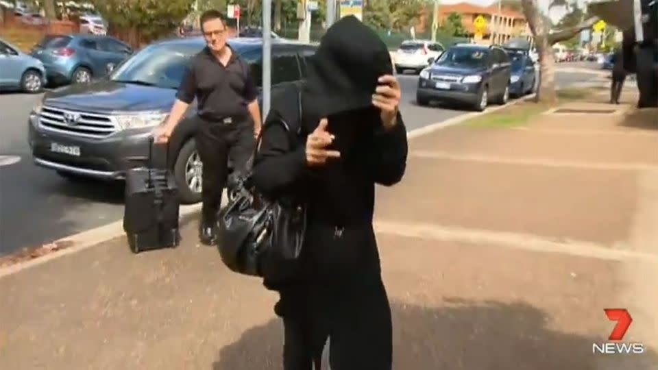 Deborah Levy can be seen covering her face with a black coat after she was an hour late to court. Photo: 7 News