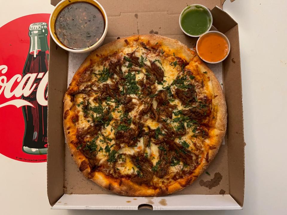 The birria pizza at South Philly's Pizza Mixta, with consome for dunking and multiple salsas.